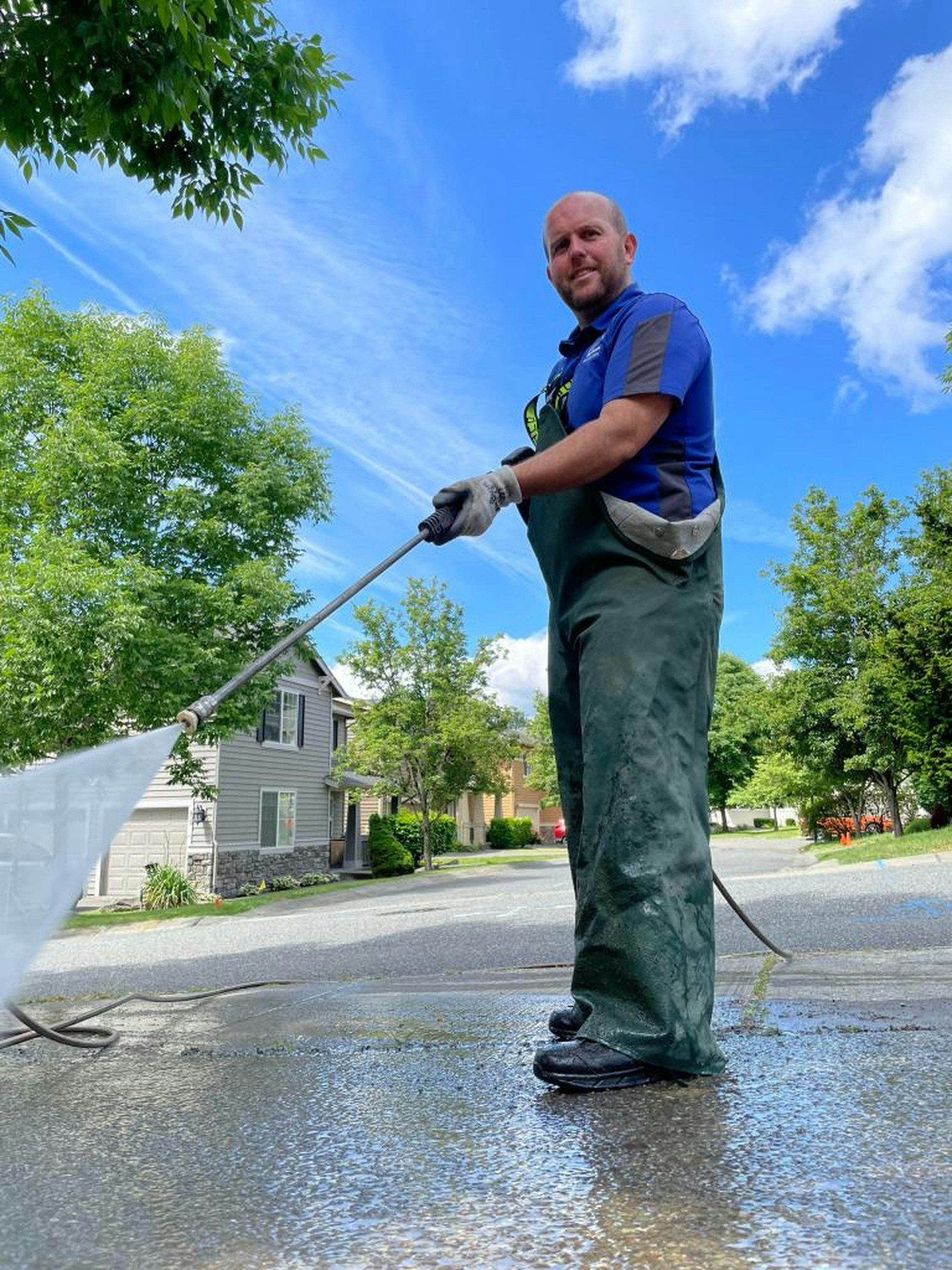 Worker pressure washing a residential driveway on a sunny day
